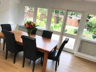a dining room with a wooden table and black chairs at Gidea Park Hotel in Romford