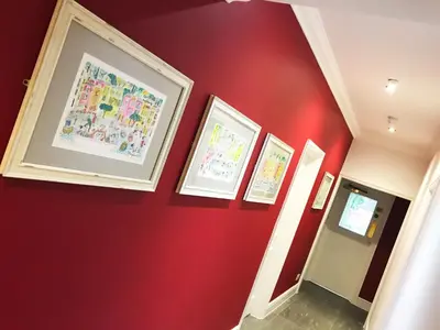 a hallway with red walls and framed pictures at Gidea Park Hotel in Romford