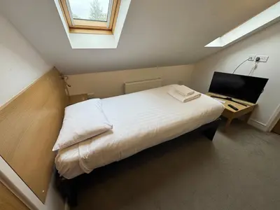 a bedroom with a bed and a desk with a computer at Gidea Park Hotel in Romford