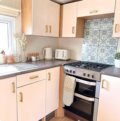 a kitchen with white cabinets and a stove top oven at Harwich - Caravan - Sleeps 10 - Garden - Pool in Harwich