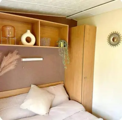 a bed in a room with a wooden cabinet at Harwich - Caravan - Sleeps 10 - Garden - Pool in Harwich