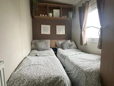 two beds in a small room with a window at Harwich - Caravan - Sleeps 10 - Garden - Pool in Harwich