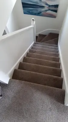 a stairway with brown carpeted stairs in a house at Modern home in historic market town near airport in Saffron Walden
