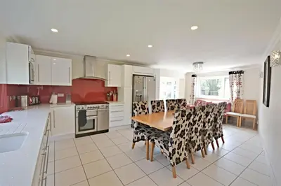 a kitchen with a table and chairs and a stove at Modern home in historic market town near airport in Saffron Walden