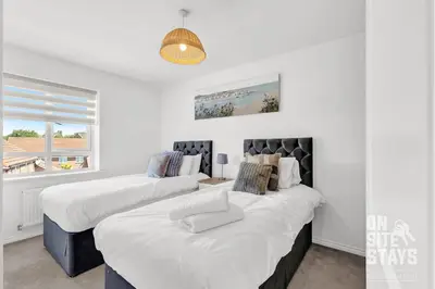 two beds in a room with white walls at OnSiteStays - 4 Large Bedrooms 3 Bathrooms 1 WC Parking Garden & Wifi in Basildon
