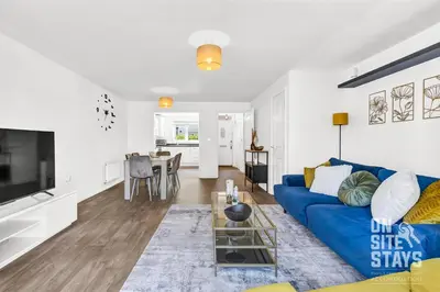 a living room with a blue couch and a table at OnSiteStays - 4 Large Bedrooms 3 Bathrooms 1 WC Parking Garden & Wifi in Basildon