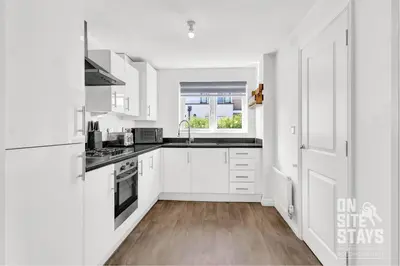 a white kitchen with white cabinets and a window at OnSiteStays - 4 Large Bedrooms 3 Bathrooms 1 WC Parking Garden & Wifi in Basildon