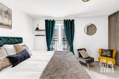 a bedroom with a large bed and a chair at OnSiteStays - 4 Large Bedrooms 3 Bathrooms 1 WC Parking Garden & Wifi in Basildon