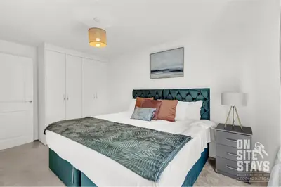 a bedroom with a large bed with a blue headboard at OnSiteStays - 4 Large Bedrooms 3 Bathrooms 1 WC Parking Garden & Wifi in Basildon