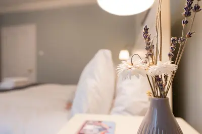 a vase with flowers on a table with a bed at Sea Holly Cottage, Aldeburgh in Aldeburgh