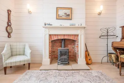 a living room with a brick fireplace and a chair at Sea Holly Cottage, Aldeburgh in Aldeburgh