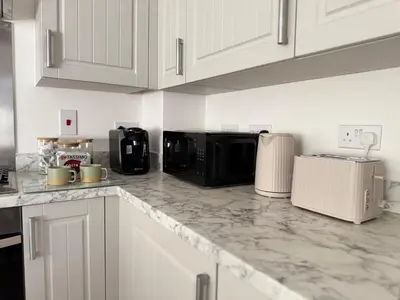 a kitchen with white cabinets and a black microwave at Modern & Elegant with Free Parking & Balcony in Cambourne