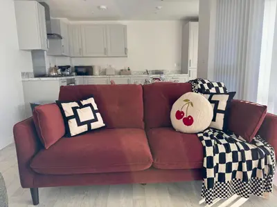 a red couch in a living room with pillows on it at Modern & Elegant with Free Parking & Balcony in Cambourne