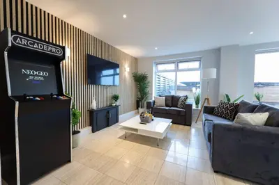a living room with a television and a living room with couches at Penthouse with Hot Tub by Cambridge Station in Cambridge