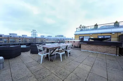 a patio with a table and chairs on a roof at Penthouse with Hot Tub by Cambridge Station in Cambridge