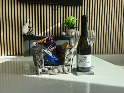 a bottle of wine and a basket of chips and a wine glass at Penthouse with Hot Tub by Cambridge Station in Cambridge