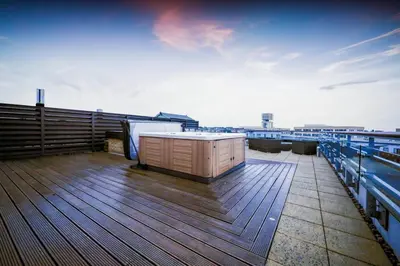 a wooden deck with a tub on top of a building at Penthouse with Hot Tub by Cambridge Station in Cambridge