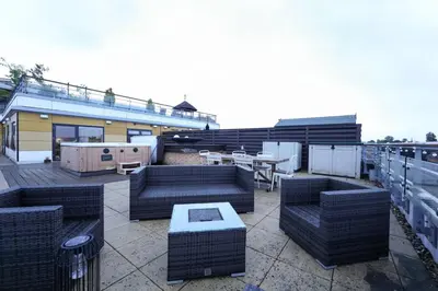 a patio with couches and tables on a building at Penthouse with Hot Tub by Cambridge Station in Cambridge