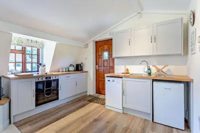 a kitchen with white cabinets and a wooden floor at 1 Bed in Hundon oc-t30616 in Hundon
