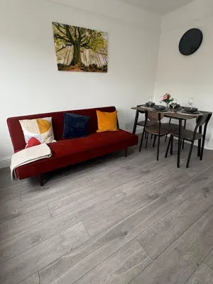 a living room with a red couch and a table at Central Chelmsford 2-Bed Apt 5 mins to Station in Chelmsford
