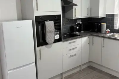 a kitchen with white cabinets and a refrigerator at Central Chelmsford 2-Bed Apt 5 mins to Station in Chelmsford