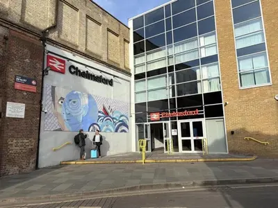 two people standing in front of a building with a mural at Central Chelmsford 2-Bed Apt 5 mins to Station in Chelmsford