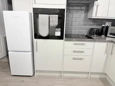 a kitchen with white cabinets and a refrigerator at Central Chelmsford 2-Bed Apt 5 mins to Station in Chelmsford