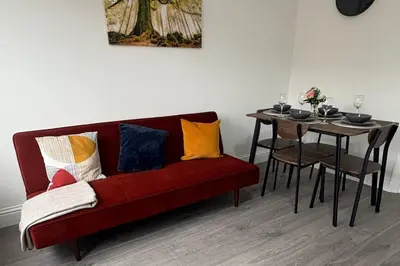 a red couch with colorful pillows next to a table at Central Chelmsford 2-Bed Apt 5 mins to Station in Chelmsford