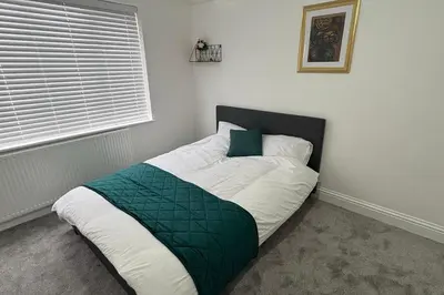 a bed in a bedroom with a green pillow on it at Central Chelmsford 2-Bed Apt 5 mins to Station in Chelmsford