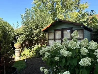 a garden with a small green house with white flowers at 3 Bed in Hingham oc-m29945 in Hingham