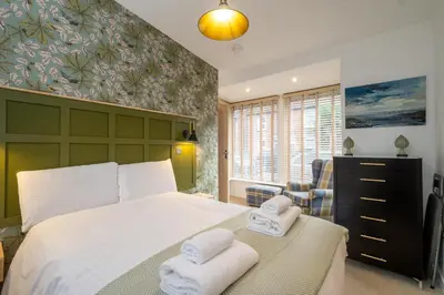 a bedroom with a large bed with towels on it at Hale House, Leiston - Aldeburgh Coastal Cottages in Leiston