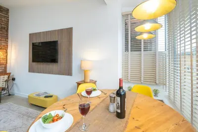 a dining room with a wooden table with a bottle of wine at Hale House, Leiston - Aldeburgh Coastal Cottages in Leiston