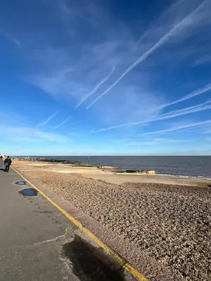 a person walking along a beach with the ocean at 4-Bedroom House 5 mins to Beach & Parking in Felixstowe