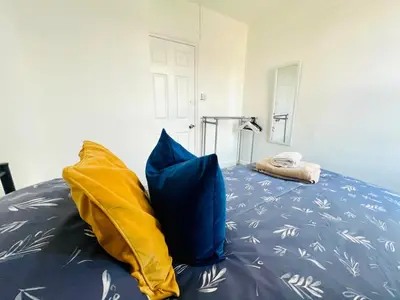 a bedroom with a bed with blue and yellow pillows at 4-Bedroom House 5 mins to Beach & Parking in Felixstowe
