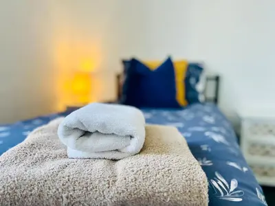 a pile of towels sitting on top of a bed at 4-Bedroom House 5 mins to Beach & Parking in Felixstowe