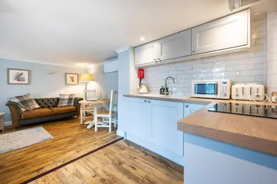 a kitchen with blue cabinets and a living room at Holly House Studio, Lavenham in Lavenham