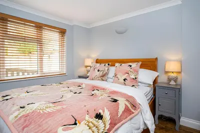 a bedroom with a bed with a pink and white comforter at Holly House Studio, Lavenham in Lavenham