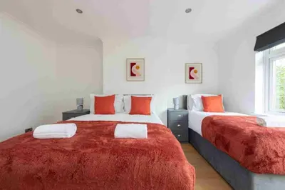 a bedroom with two beds with red and white sheets at 5 Bed House in Romford 9 Beds in Havering atte Bower