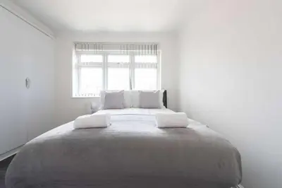 a large bed in a white room with a window at 5 Bed House in Romford 9 Beds in Havering atte Bower