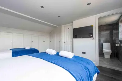 a bedroom with a large bed with blue and white sheets at 5 Bed House in Romford 9 Beds in Havering atte Bower