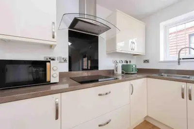 a white kitchen with a sink and a microwave at 5 Bed House in Romford 9 Beds in Havering atte Bower