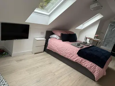 a bedroom with a bed and a flat screen tv at The Cartlodge - Studio Loft Apartment in Horringer, Bury St Edmunds in Westley
