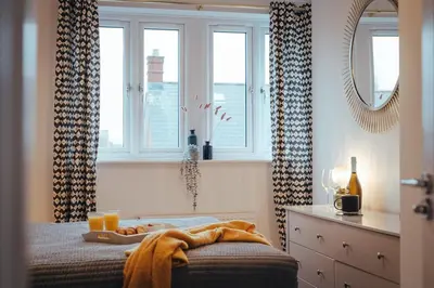 a bedroom with a bed and a mirror and windows at 5 Bed Family Home- Free Parking in Woodham Ferrers Station