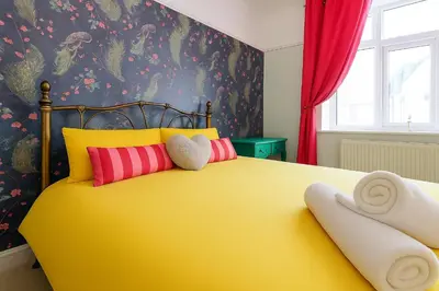 a yellow bed with colorful pillows in a bedroom at 2 Bed Apartment- Leigh Broadway in Southend-on-Sea
