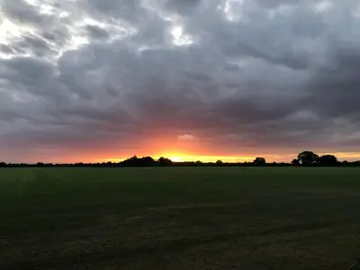 a cloudy sky over a field with the sun setting at Country View place in Weeley