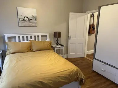 a bedroom with a bed with yellow sheets and a guitar at Haven Hideaway in Harwich