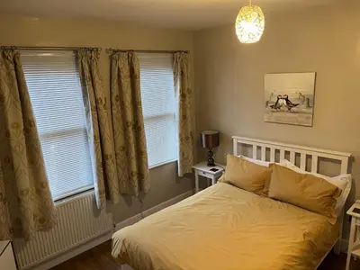 a bedroom with a bed and two windows at Haven Hideaway in Harwich