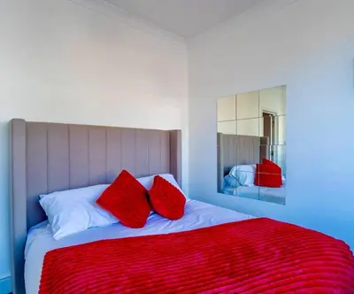 a bedroom with a large bed with red pillows at Rayleigh Retreat-Spacious Family 3 Bed Apartment in Rayleigh