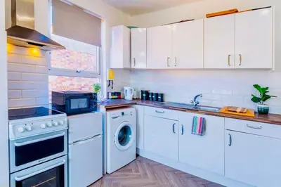 a kitchen with white cabinets and a washer and dryer at Rayleigh Retreat-Spacious Family 3 Bed Apartment in Rayleigh