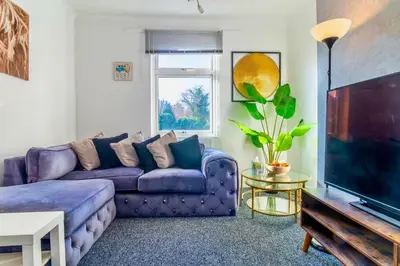 a living room with a purple couch and a tv at Rayleigh Retreat-Spacious Family 3 Bed Apartment in Rayleigh